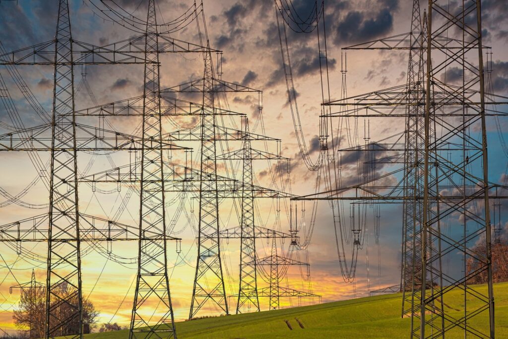 A row of electrical towers with the sunset behind them